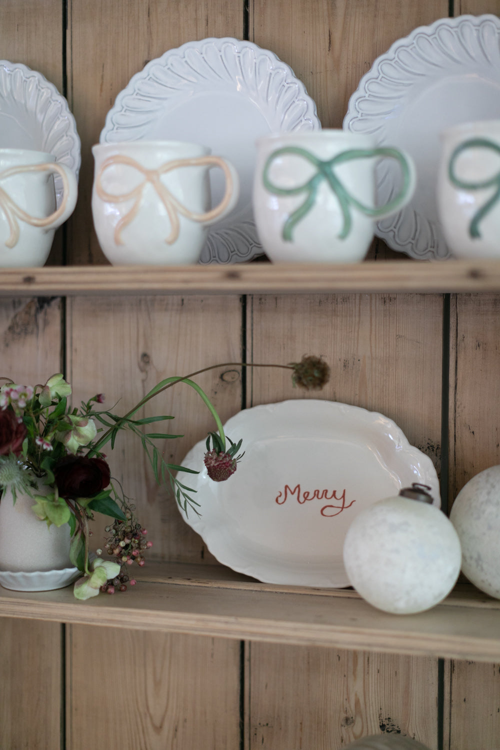 Decorative ceramic items on a wooden shelf with a rustic background