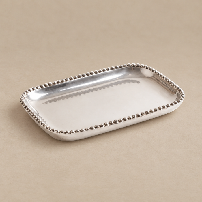A rectangular silver tray with a beaded border, photographed on a plain beige background.