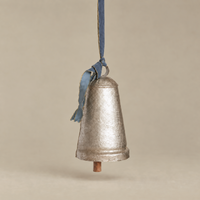 A vintage-style galvanized metal bell ornament hanging from a blue ribbon, set against a solid beige background.