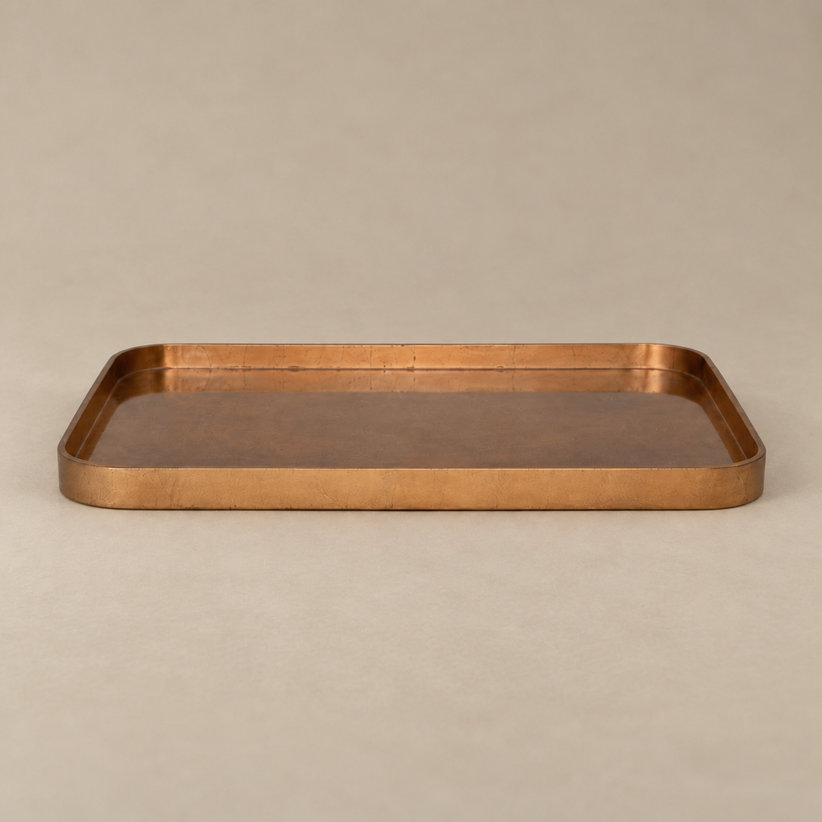 A rectangular copper tray with a hammered texture and raised rim, shown on a neutral beige background.