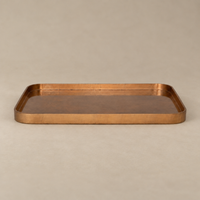 A rectangular copper tray with a hammered texture and raised rim, shown on a neutral beige background.