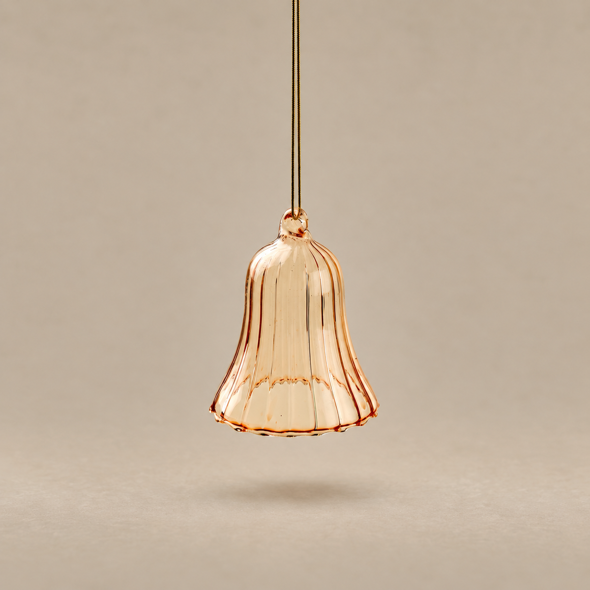 A single hanging pendant light shade made of translucent ribbed glass in a warm peachy rose-gold tone, suspended against a plain beige background.